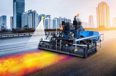 Blue asphlat paver equipped with Pave-IR system with thermal reading projected on asphalt surface.